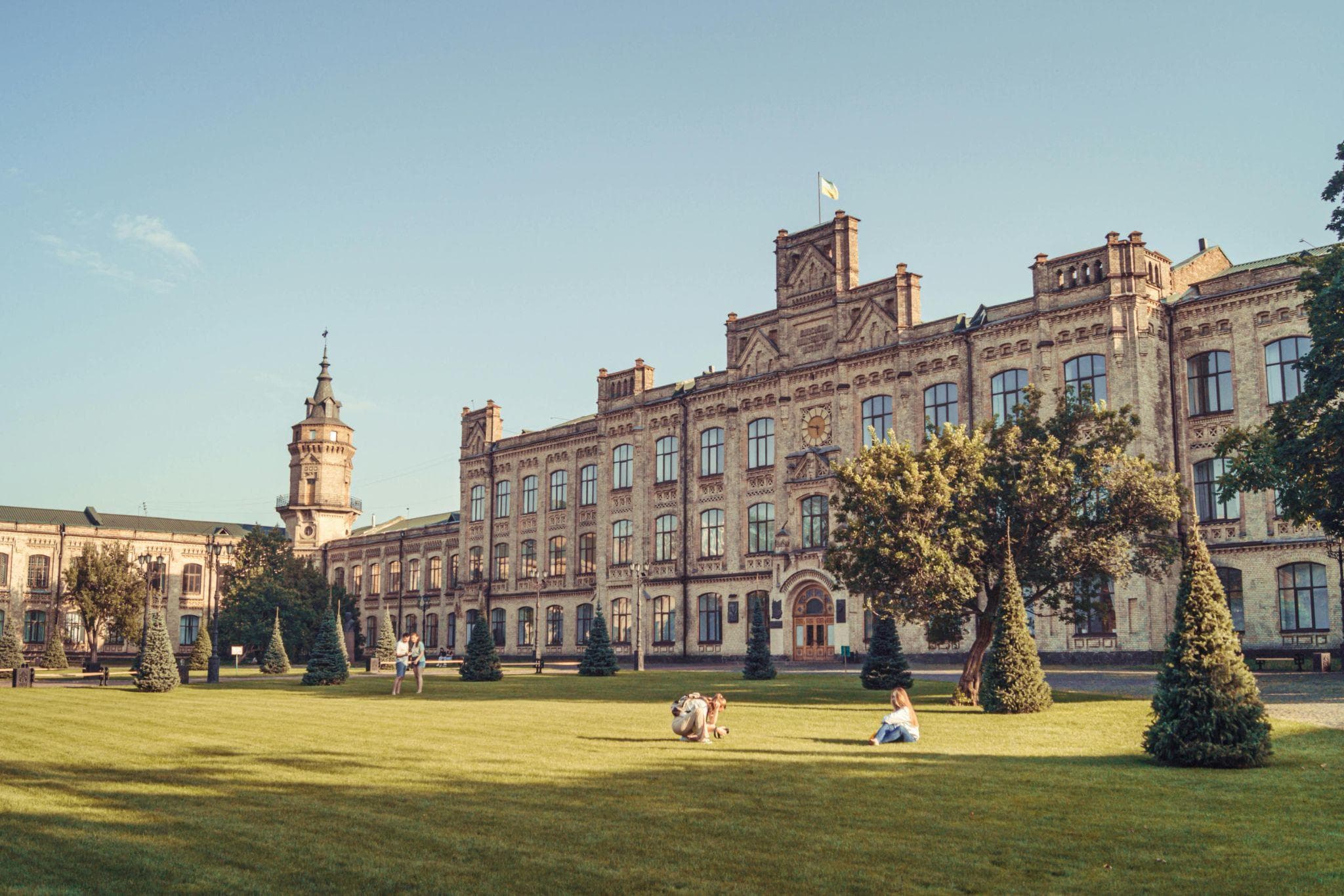 Students sit on the lawn in front of the historic, stone-built Igor Sikorsky Kyiv Polytechnic Institute.